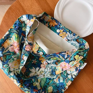 Detail of floral canvas tote bag showing metal magnetic buckle and simple wish label