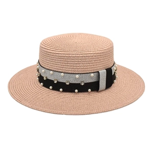 Close-up of pink straw boater hat with decorative pearl and rhinestone band details