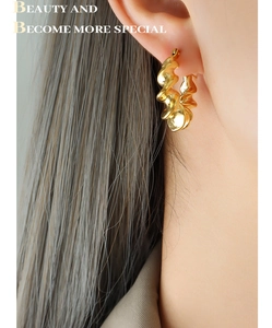 Close-up of elegant gold twisted C-shape earrings on model showing spiral design details