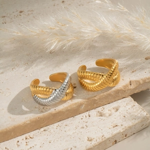 Textured criss-cross open rings in 18k gold plating on a natural stone surface