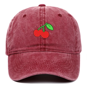 Close-up of cherry embroidery and vintage washed denim texture on a burgundy baseball cap