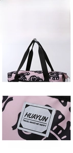 Detail of pink travel bag with black elephant print, woven handles and brand label