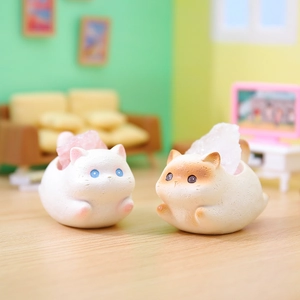 Close-up of cute white and beige cat figurines with pink crystal stones on a mini sofa