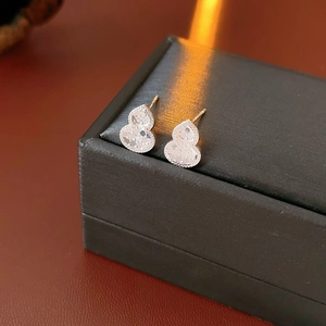 Macro shot of silver gourd-shaped stud earrings featuring intricate surface texture