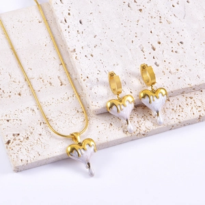 Golden heart jewelry set featuring white pearlescent enamel necklace and stud earrings