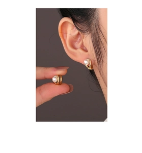 Macro shot of 14K gold plated silver earring with elegant twisted metal and pearl