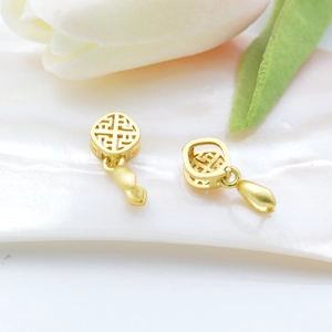 Elegant gold drop earrings with geometric patterns displayed near white tulips