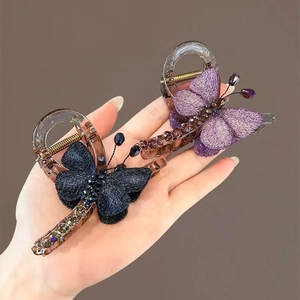 Handheld butterfly hair claw clips in purple and deep blue with glitter fabric and crystals