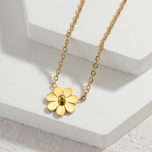 Gros plan du collier avec pendentif fleur marguerite dorée sur socle géométrique blanc