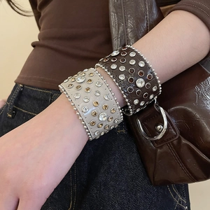 Détail de larges bracelets en cuir avec strass et bordure perlée sur un mannequin