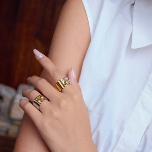 Detail of wide stainless steel cherry rings in gold and silver on a model's hand