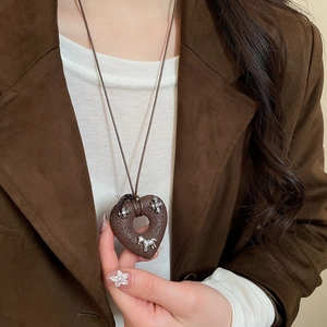 Detail of dark brown heart necklace with silver star and pony inlays worn on a brown blazer