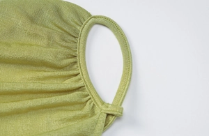 Gros plan détaillé du masque en tricot vert clair montrant l'attache élastique et le tissu