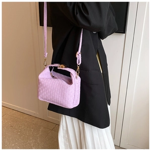 Detail of light purple woven handbag with gold lock and adjustable shoulder strap