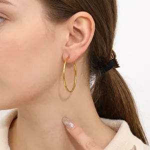 Close-up of 4cm gold-plated stainless steel hoop earrings worn by a female model