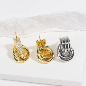 Detailed view of layered gold and silver hoop earrings on white stone display