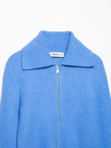 Detail of sky blue knit sweater showing zip-up collar and soft brushed fabric texture