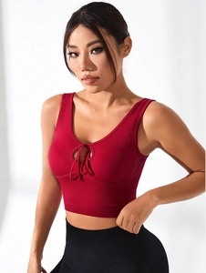 Detail view of red ribbed sports bra featuring a deep V-neckline and tie-up chest detail