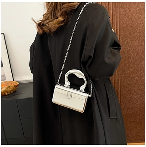 Close-up of a silver mirror acrylic clutch bag with a metal chain on a black coat