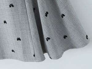 Detailed macro view of gray herringbone fabric featuring 3D black velvet bow appliques