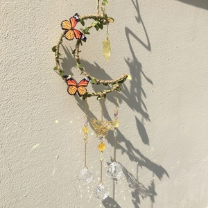 Detail of moon suncatcher with crystals, green leaves and vivid butterfly ornaments