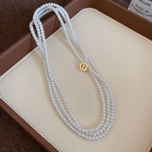 Macro detail of triple-layer pearl necklace with vintage gold floral OT toggle clasp