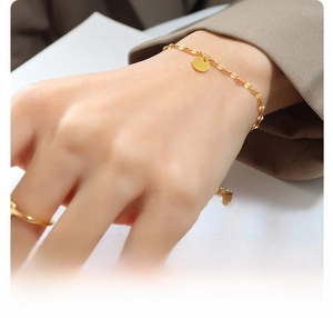 Detail of minimalist 18K gold plated titanium steel bracelet with a round disc charm