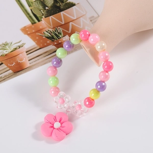 Colorful beaded kids bracelet with pink flower pendant on a model's wrist