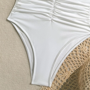 Detail of pearl white one-piece swimsuit featuring textured ruching and premium fabric