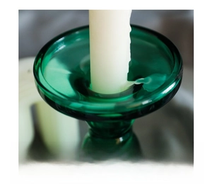 Detail of rounded candle holder rim in green glass with smooth polished edges