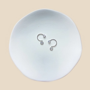 Macro detail of silver stainless steel nipple ring with round and square cubic zirconia