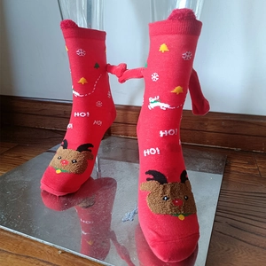Detail of red Christmas socks with 3D arms and reindeer pattern on a transparent foot mold