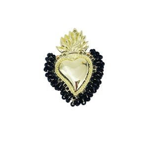 Detail of handmade heart pendant with black beads and gold flame accent on white backdrop