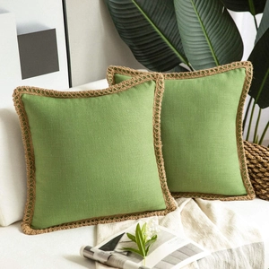 Detail of green linen pillow covers with braided jute trim on a beige sofa
