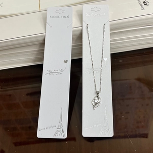 Close-up of stainless steel heart necklace on jewelry display card with romantic text