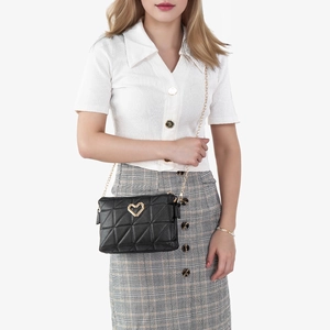 Quilted black crossbody bag with gold heart lock and chain strap on a model