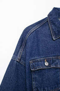 Detail of dark blue denim jacket collar and chest pocket with contrast stitching