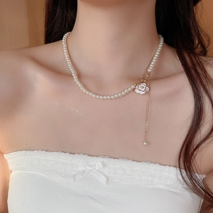 Detailed close-up of French vintage pearl necklace with camellia pendant and gold tassel
