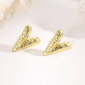Close-up of golden abstract heart stud earring with irregular hammered metal texture