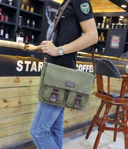 Detail of army green canvas messenger bag with leather straps in a cafe setting