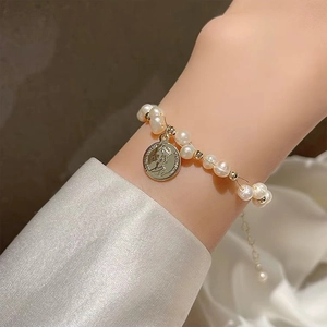 Detailed shot of baroque freshwater pearls and gold coin pendant on a delicate bracelet