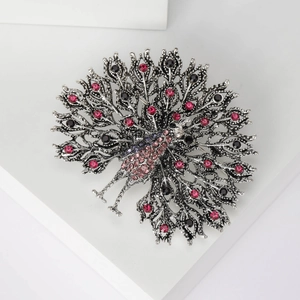 Detail of vintage peacock brooch with pink and purple rhinestones on white stand