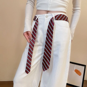 Detail of red and blue striped silk scarf belt paired with white denim wide-leg jeans
