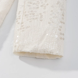 Dettaglio macro del tessuto con paillettes beige sul polsino della giacca di lusso