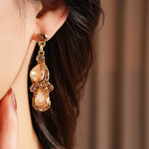 Gros plan de boucles d'oreilles vintage dorées avec cristaux champagne étincelants taillés en poire