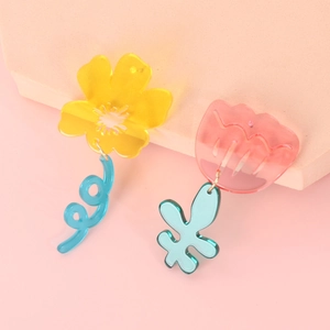 Detail view of asymmetric acrylic flower earrings with yellow and pink floral design