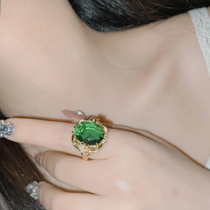 Close-up of a large green oval gemstone ring in gold setting with fine diamond accents