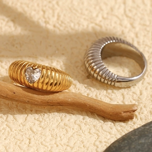 Detail of 18K gold croissant ring featuring a heart-shaped zircon and ribbed texture