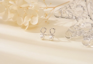 Close-up of S925 silver twist pearl earrings with infinity design and dried flowers