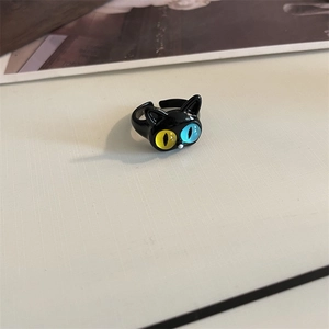 Detail of black cat ring featuring unique yellow and blue heterochromia eyes and adjustable band